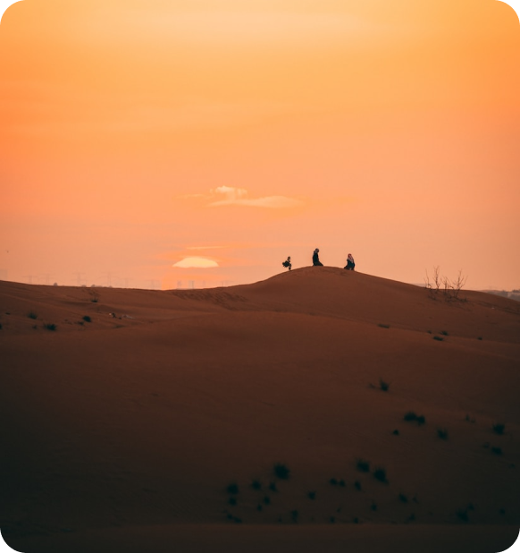 Two people in desert watching sunset